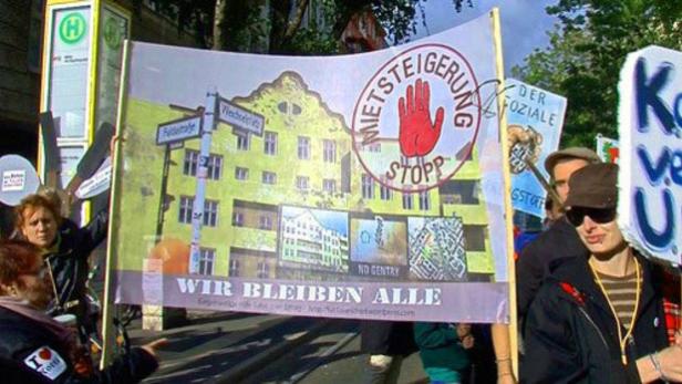 Demonstranten halten ein Banner mit der Aufschrift „Mietsteigerung Stopp“ und „Wir bleiben alle“.