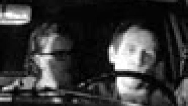 Zwei Personen sitzen in einem Auto, die Fahrerin blickt nach vorne.