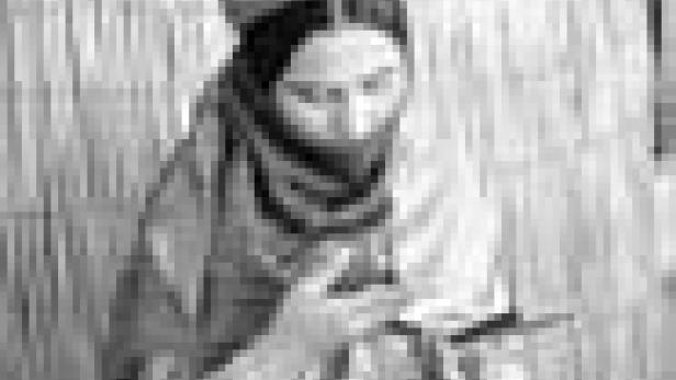 Eine Frau mit traditioneller Kopfbedeckung liest ein Buch.