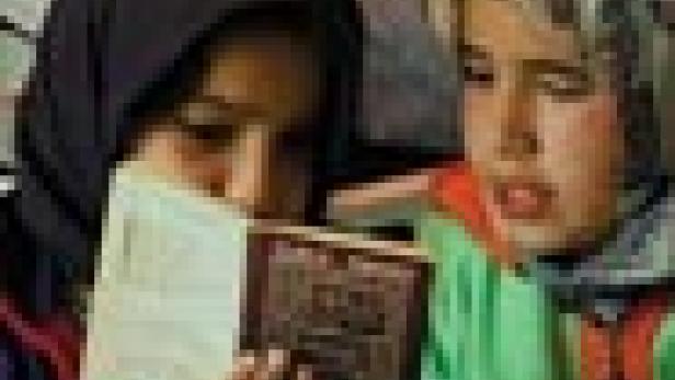 Zwei junge Mädchen lesen gemeinsam in einem Buch.