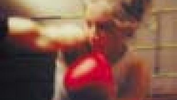 Eine Frau boxt mit roten Boxhandschuhen.