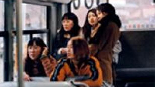 Eine Gruppe junger Frauen steht oder sitzt in einem Bus und schaut aus dem Fenster.