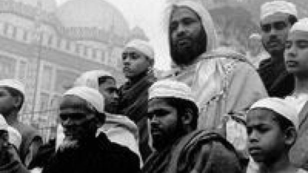 Eine Gruppe muslimischer Männer und Jungen steht vor einer Moschee.