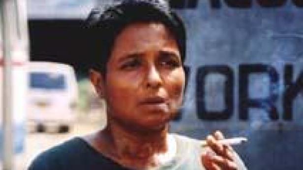 Eine Frau mit kurzen Haaren raucht eine Zigarette.