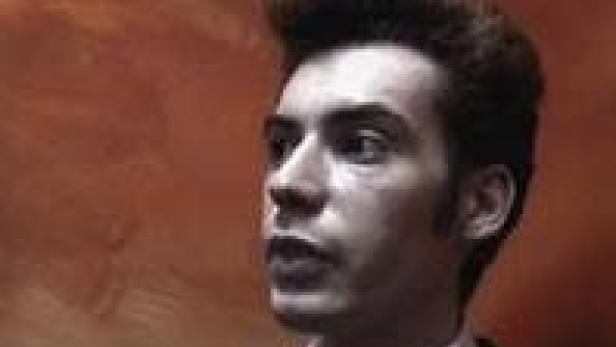 Ein Mann mit hochgestyltem Haar blickt zur Seite.