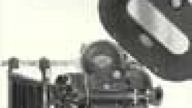 Eine alte Filmkamera mit Gegenlichtblende vor einem hellen Hintergrund.