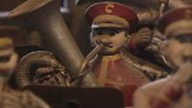 Eine Spielzeugband mit Musikern in roten Uniformen spielt auf ihren Instrumenten.