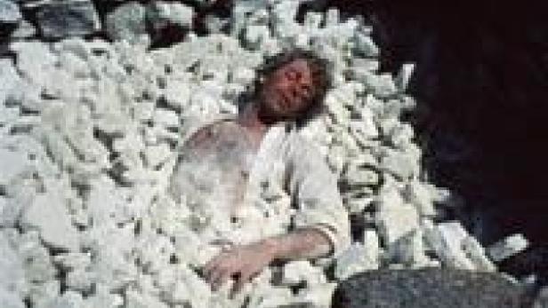 Ein Mann liegt inmitten eines Haufens weißer Steine.