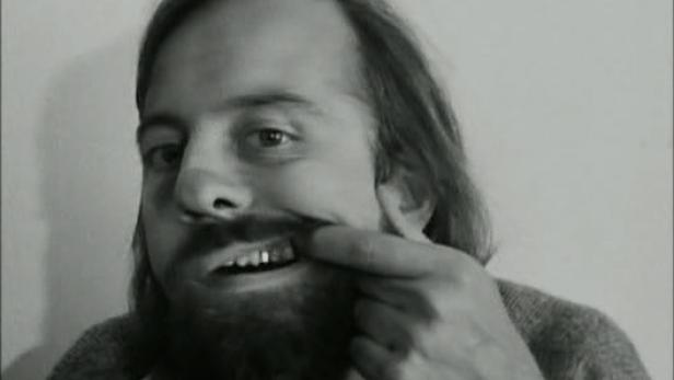 Ein Mann mit Bart zieht an seiner Unterlippe.