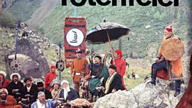 Eine Gruppe von Menschen in traditioneller Kleidung vor einer Bergkulisse bei einer Totenfeier.