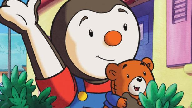 Der kleine Zeichentrick-Pinguin Caillou winkt mit seinem Teddybären im Arm.