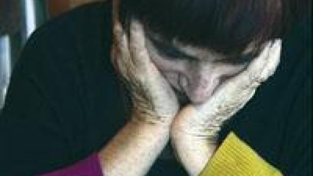 Eine Frau mit roten Haaren stützt ihren Kopf in ihre Hände.