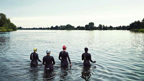 Das Filmplakat für „Wechselzeiten“ zeigt vier Triathletinnen, die in ein Gewässer waten.