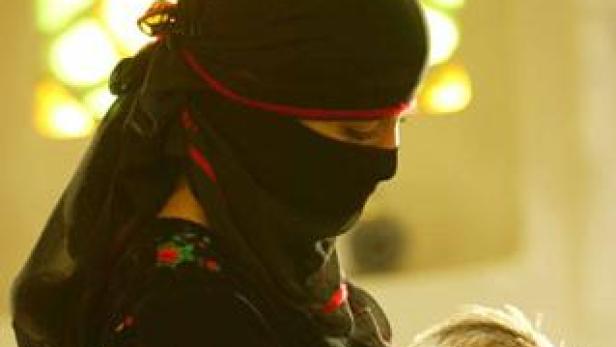 Eine Frau mit schwarzem Niqab blickt nach unten.