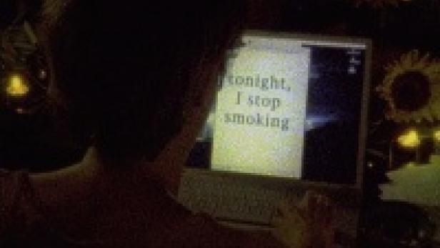Eine Person tippt auf einem Laptop, auf dessen Bildschirm der Text „Tonight, I stop smoking“ zu sehen ist.