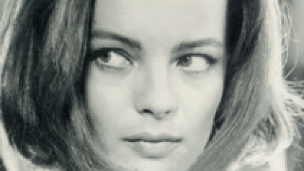 Schwarzweißporträt der Schauspielerin Romy Schneider, die über ihre Schulter blickt.