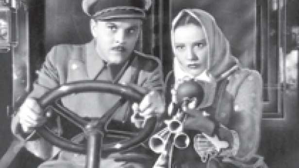 Ein Mann mit Mütze und Uniform und eine Frau mit Kopftuch sitzen in einem Fahrzeug.