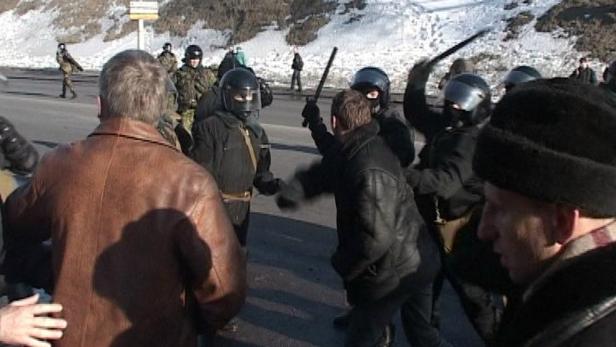 Polizisten in Kampfmontur setzen Schlagstöcke gegen Demonstranten ein.