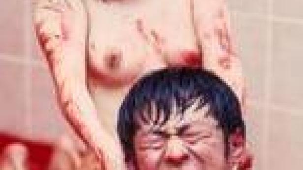 Eine blutverschmierte Frau steht hinter einem Mann und würgt ihn.