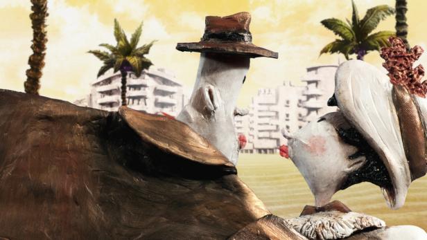 Eine skulpturale Darstellung zweier stilisierter Figuren mit Hüten vor einer tropischen Stadtlandschaft.