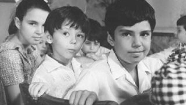 Eine Gruppe von Kindern sitzt an einem Tisch, vermutlich in einem Klassenzimmer.