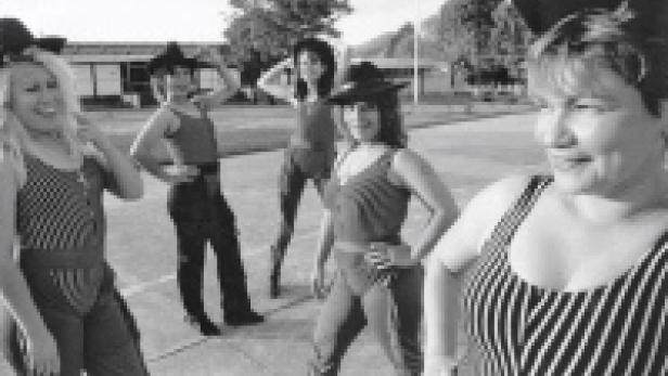 Fünf Frauen posieren in gestreiften Badeanzügen und Hüten im Freien.