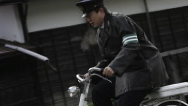 Ein uniformierter Mann fährt mit einem Fahrrad auf einer Straße.