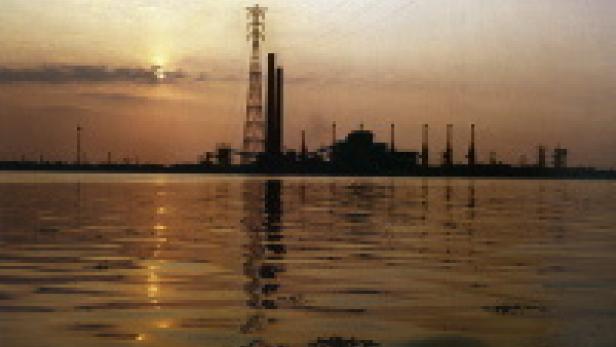 Eine Industrieanlage am Wasser bei Sonnenuntergang.