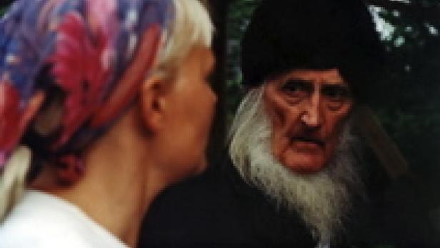 Eine Frau mit Kopftuch spricht mit einem älteren Mann mit langem Bart und schwarzem Hut.
