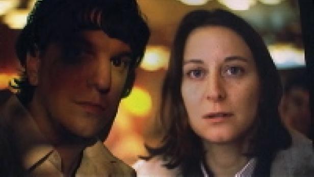 Ein Mann und eine Frau sitzen nebeneinander und schauen in die Ferne.