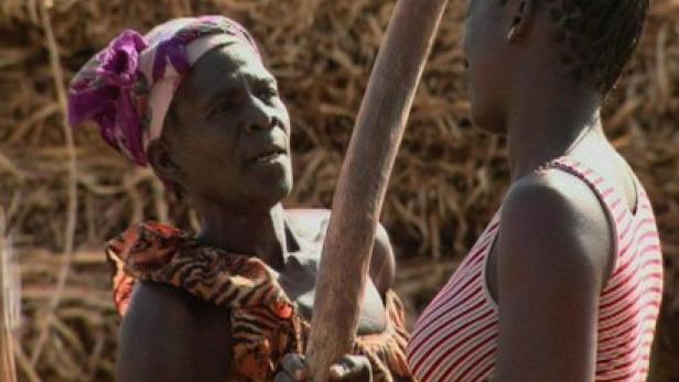 Eine ältere Frau mit Kopftuch spricht mit einer jüngeren Frau.