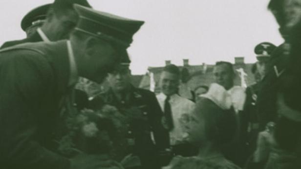 Ein Mann in Uniform überreicht einem kleinen Mädchen einen Blumenstrauß.