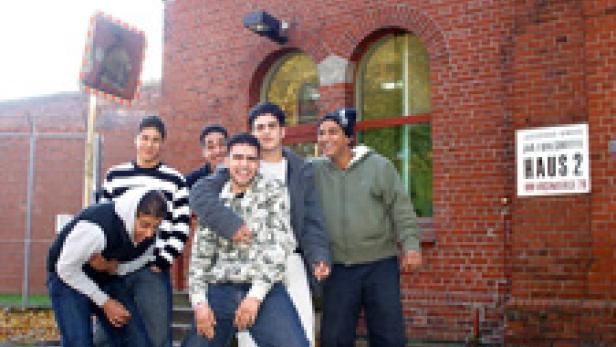 Eine Gruppe junger Männer posiert vor einem Backsteingebäude.