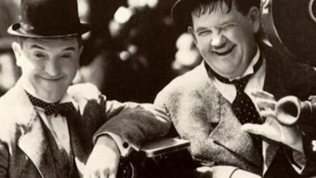 Stan Laurel und Oliver Hardy posieren lächelnd für ein Foto.
