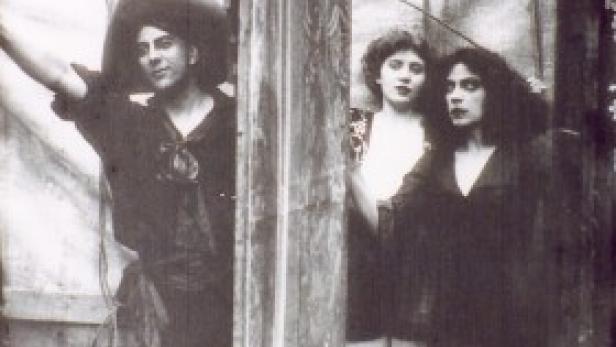 Drei Personen posieren in einem verblichenen Schwarzweißfoto.