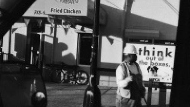 Ein Bauarbeiter steht vor einem Restaurant mit der Aufschrift „Fried Chicken“.