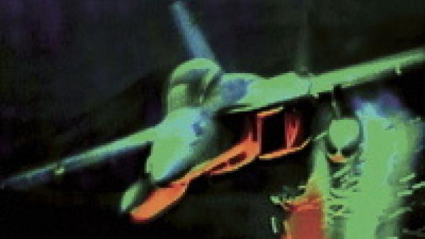 Ein Kampfjet fliegt in der Dunkelheit und schießt Leuchtspurmunition ab.