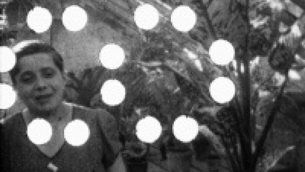 Eine Frau steht vor einer Pflanze in einem Gewächshaus.