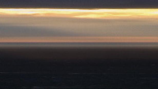 Ein dunkler Horizont unter einem bewölkten Himmel bei Sonnenaufgang oder Sonnenuntergang.