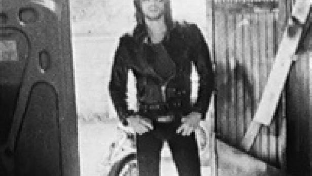 Ein Mann in Lederjacke posiert vor einem Motorrad.