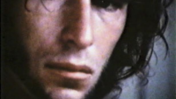 Nahaufnahme eines Mannes mit dunklen, gewellten Haaren.