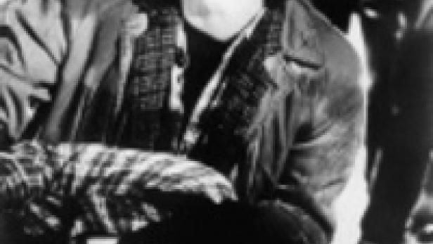 Eine junge Frau blickt besorgt nach oben, während sie eine andere Person stützt.