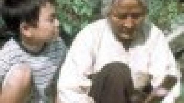 Eine ältere Frau sitzt mit einem Jungen zusammen und zeigt ihm etwas.