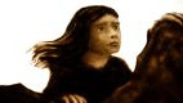 Ein junges Mädchen mit dunklen Haaren reitet auf einem Pferd.