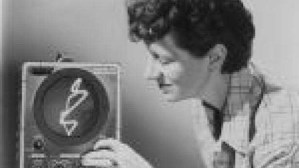 Eine Frau bedient ein Oszilloskop mit einer wellenförmigen Darstellung auf dem Bildschirm.