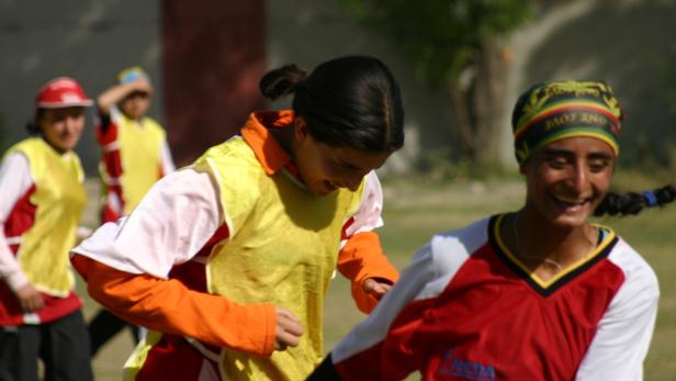 Lächelnde junge Frauen in Sportkleidung laufen im Freien.