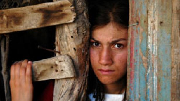 Ein junges Mädchen steht in einer Türöffnung und blickt ernst in die Kamera.