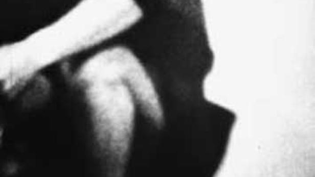 Nahaufnahme einer Person, die im Dunkeln sitzt.