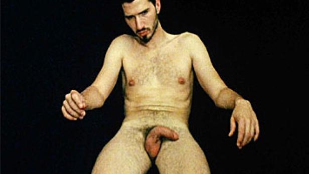 Ein Mann sitzt nackt vor einem schwarzen Hintergrund.