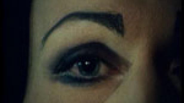 Nahaufnahme eines weiblichen Auges mit dunklem Lidschatten und definierter Augenbraue.